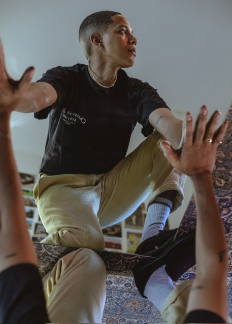 Sxdated in dynamic pose wearing black shirt and light pants